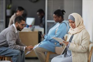 Men and woman waiting in a medical office filling out paper work. 